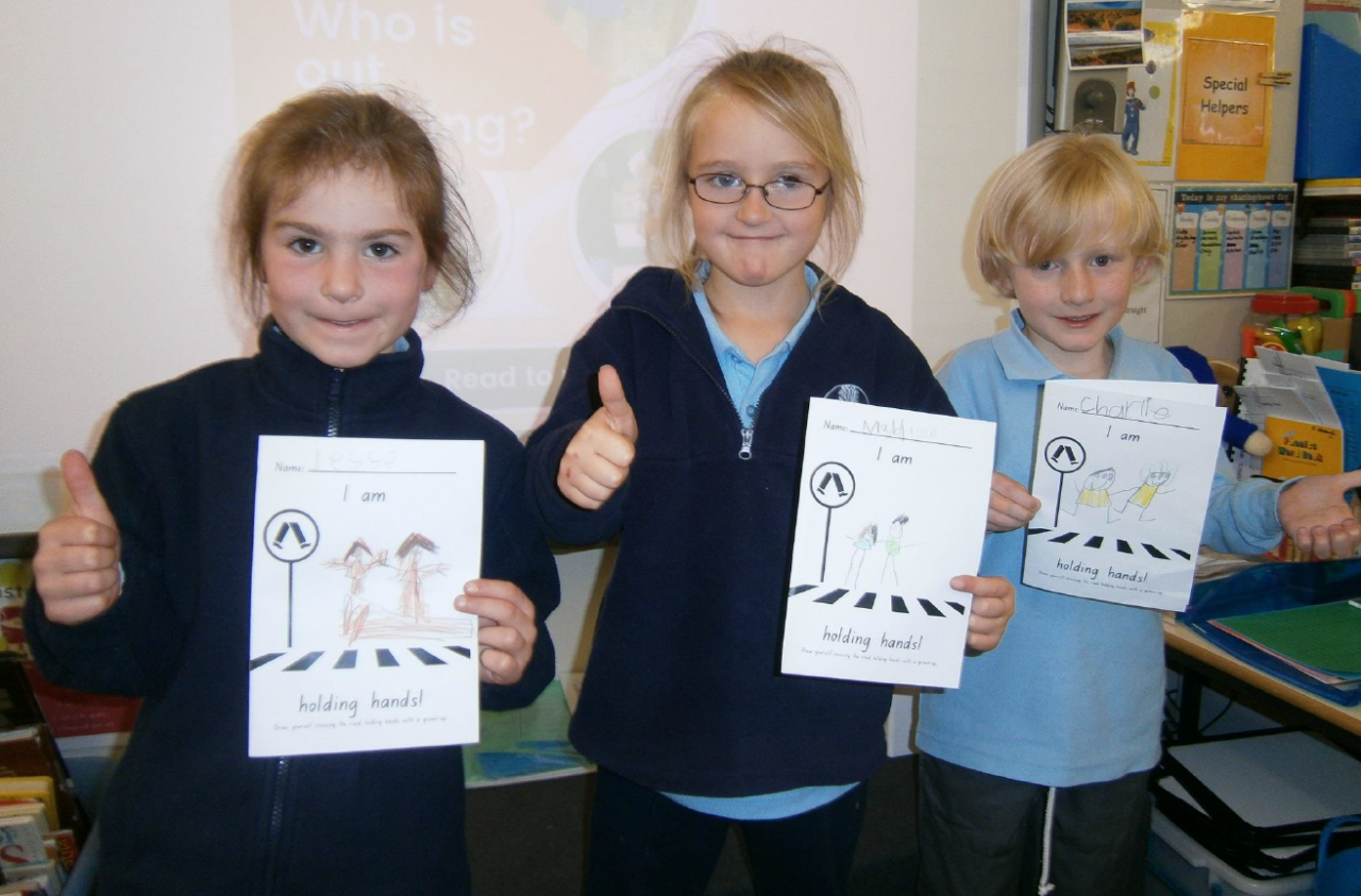 Three students showing off their holding hands activity cards.