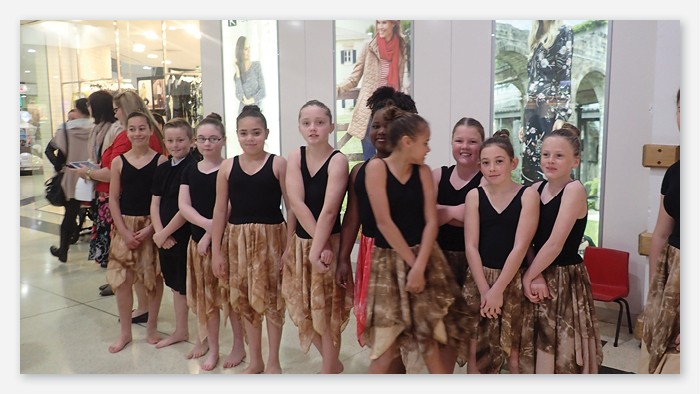 A group of Ashmont public school students in long brown skirts preparing for a dance performance.