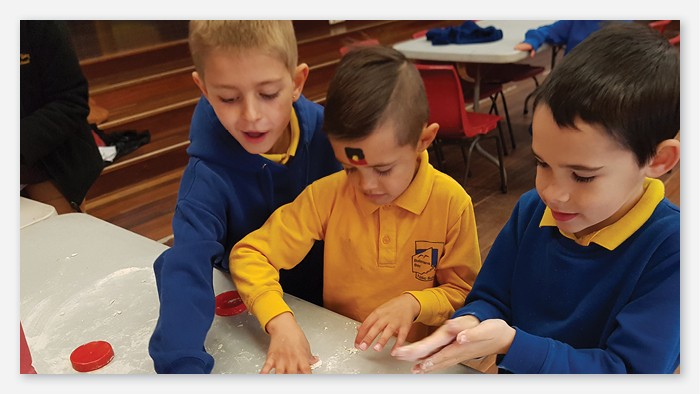 FThree Batemans bay public school students excitedly playing with flour.
