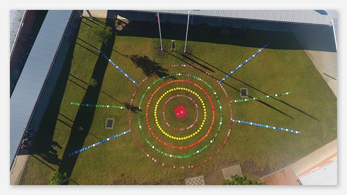 A birds eye view of a field. Coloured tiles have been placed in a specific pattern to represent Aboriginal art..