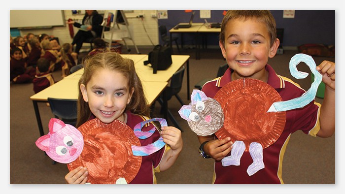 Two Westport public school students hold up animal artworks made from paper plates and coloured paper.
