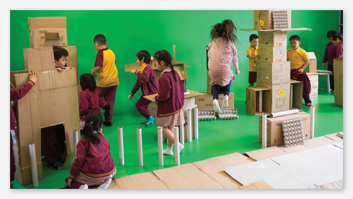 A whole class of primary students build towers out of cardboard boxes.