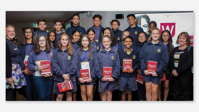 A large group of Rooty Hill students stand in rows. Each student holds a book entitled letter to my teenage self.