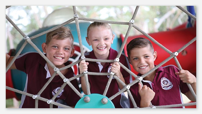 Three young male students pose on playground equipment.