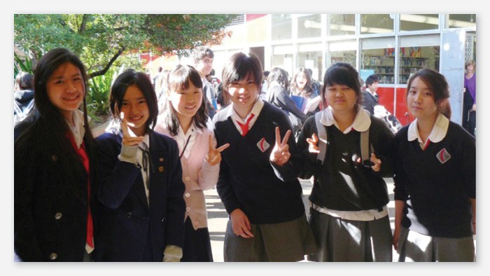 Six students smiling at the camera and making peace signs with their fingers.
