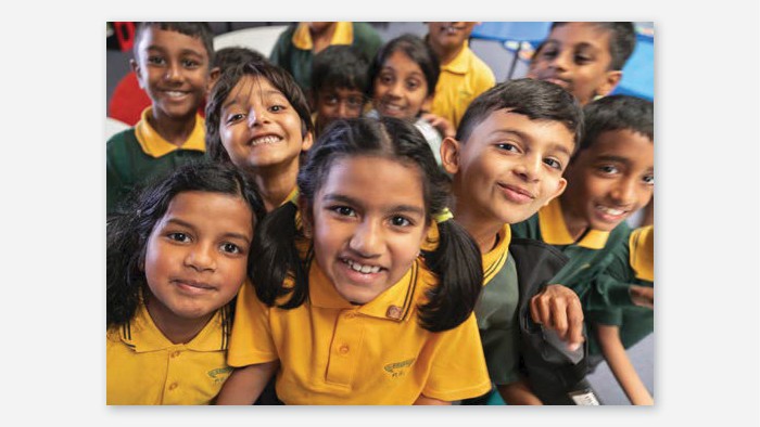 A large groupd of young students wearing Girraween school uniform smiling at the camera.