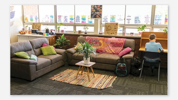The schools Intervention Centre is a cosy room with two couches, colourful rug and cushions. The room also has motivational quotes on posters, fruit and plants. There is a child doing work at a desk.