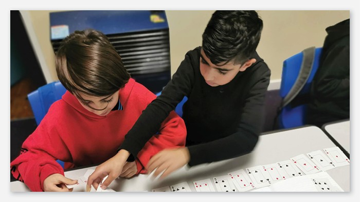 Two students play a game of cards with each other in the classroom.