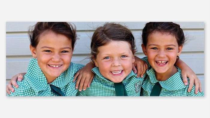 Three primary school students smiling at camera