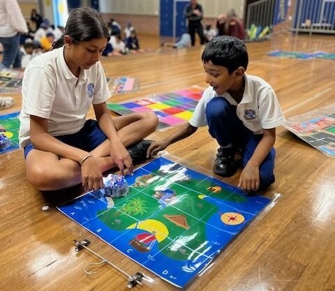 Younger student and older student playing board game at school