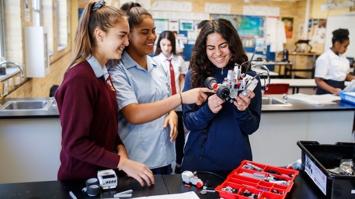 High school students in STEM class laughing holding mechanical object