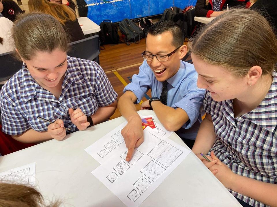 Eddie Woo seated at classroom table with 2 female Albury High students