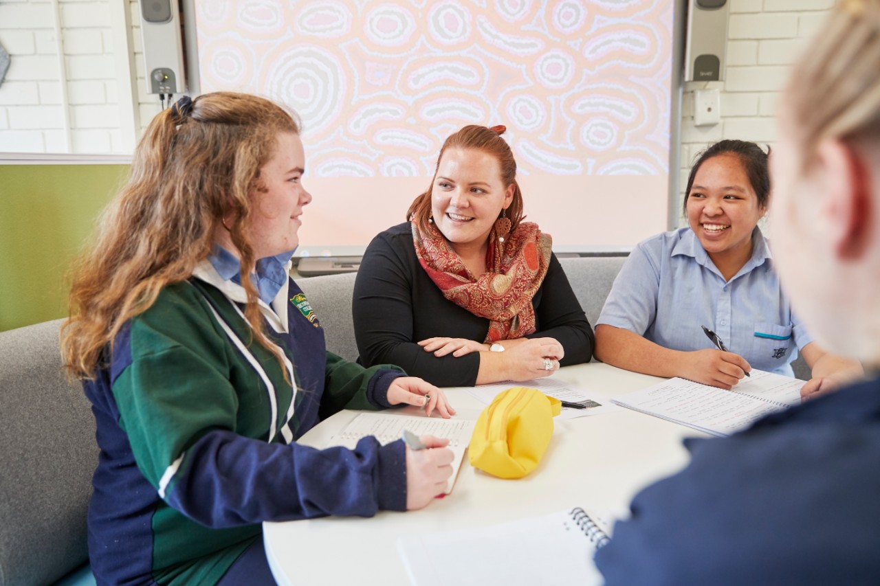 Students sitting around table with classroom teacher.