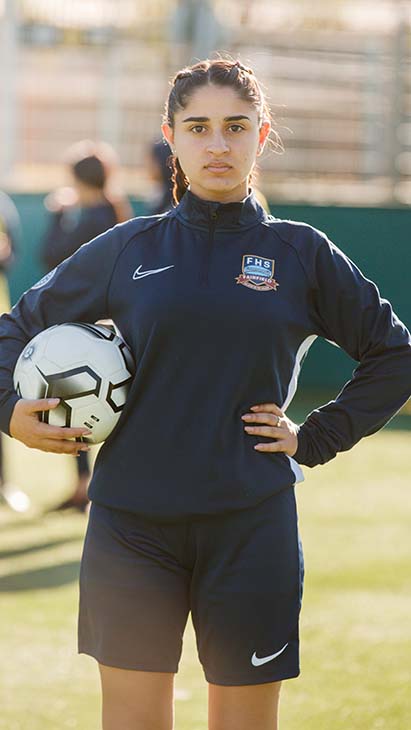 Student holding a soccer ball on the field.