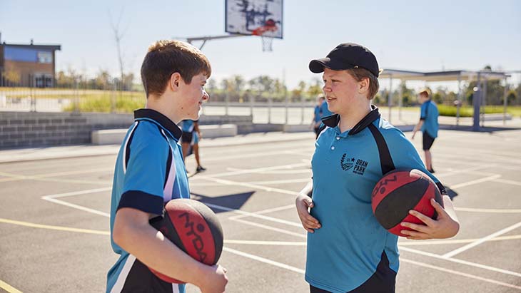 Students on the basketball court talking to eachother.