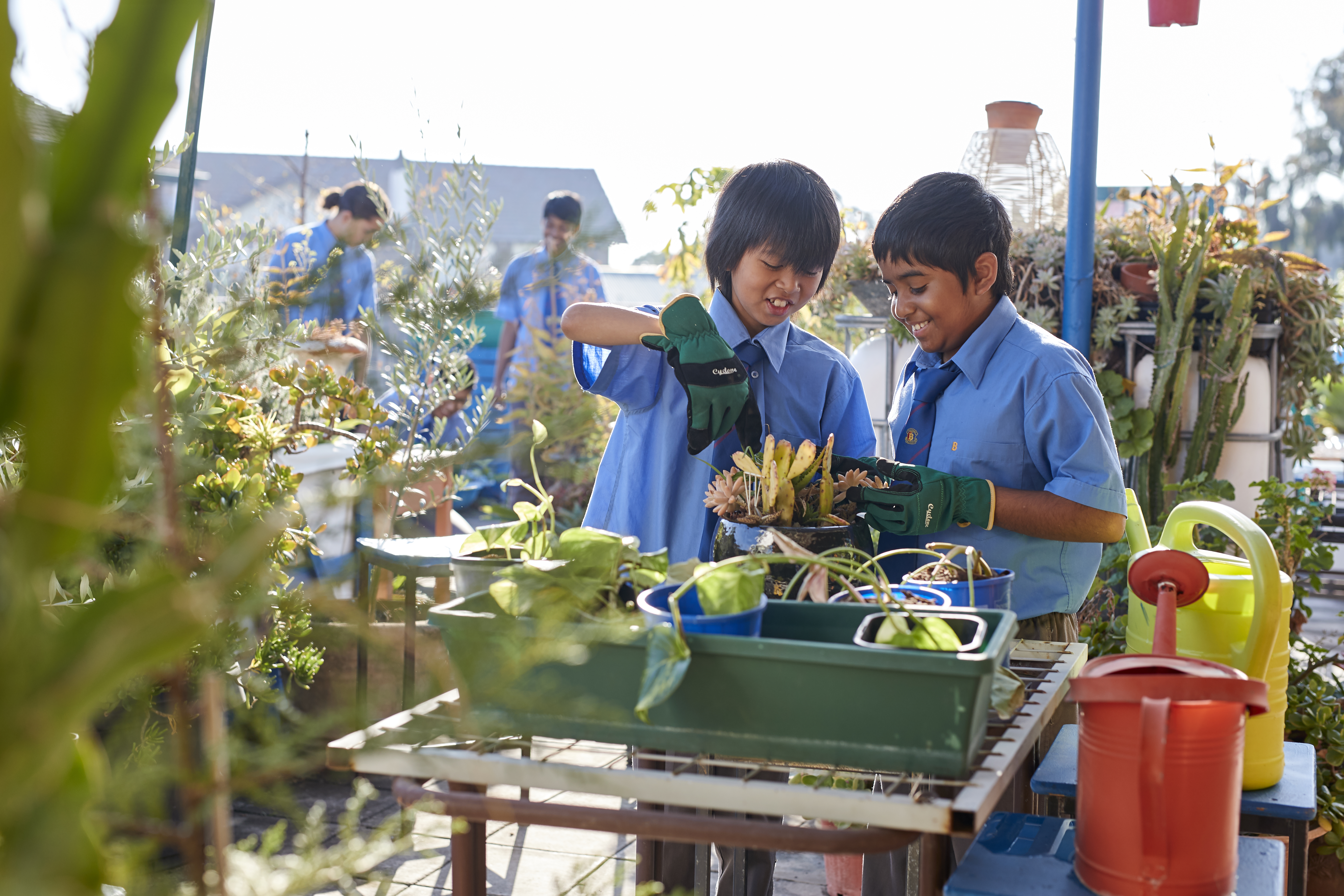 Students outside touching plants with gloves