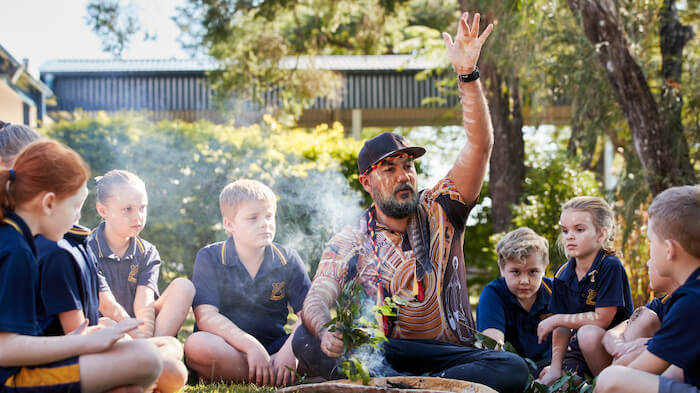 Man talking to chlldren in a circle round a camp fire