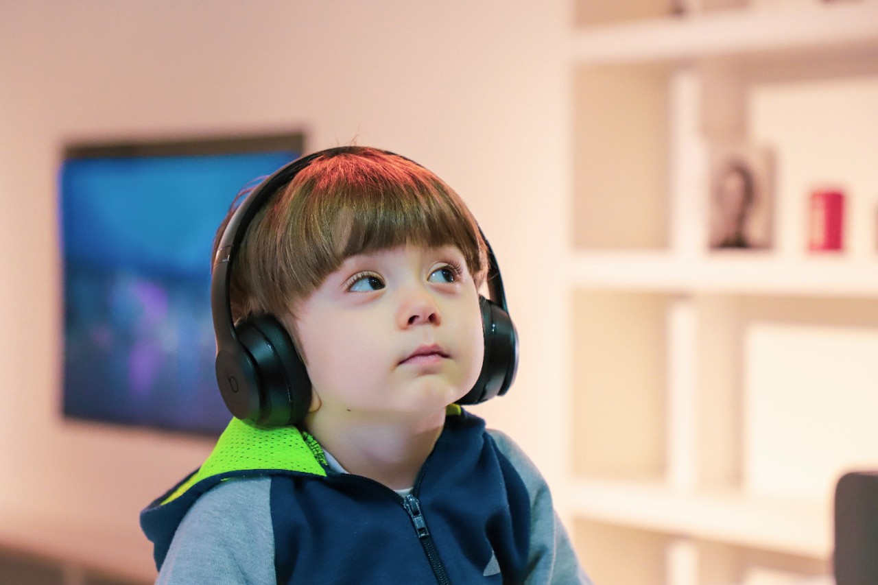 Child with headphones on looking at a screen.