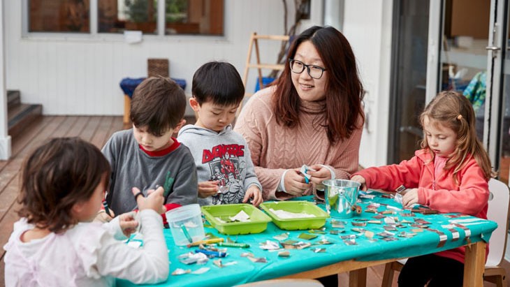 Teacher and children making crafts at table