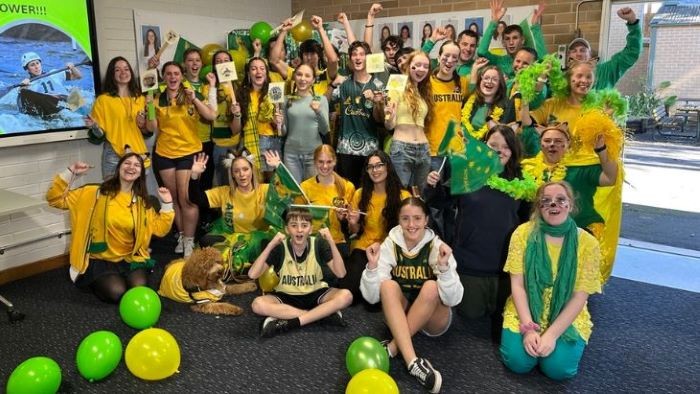 Group of students dressed in green and gold clothing cheering
