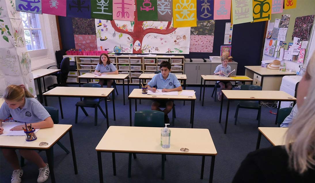 Students sit one desk apart from each other in the classroom.
