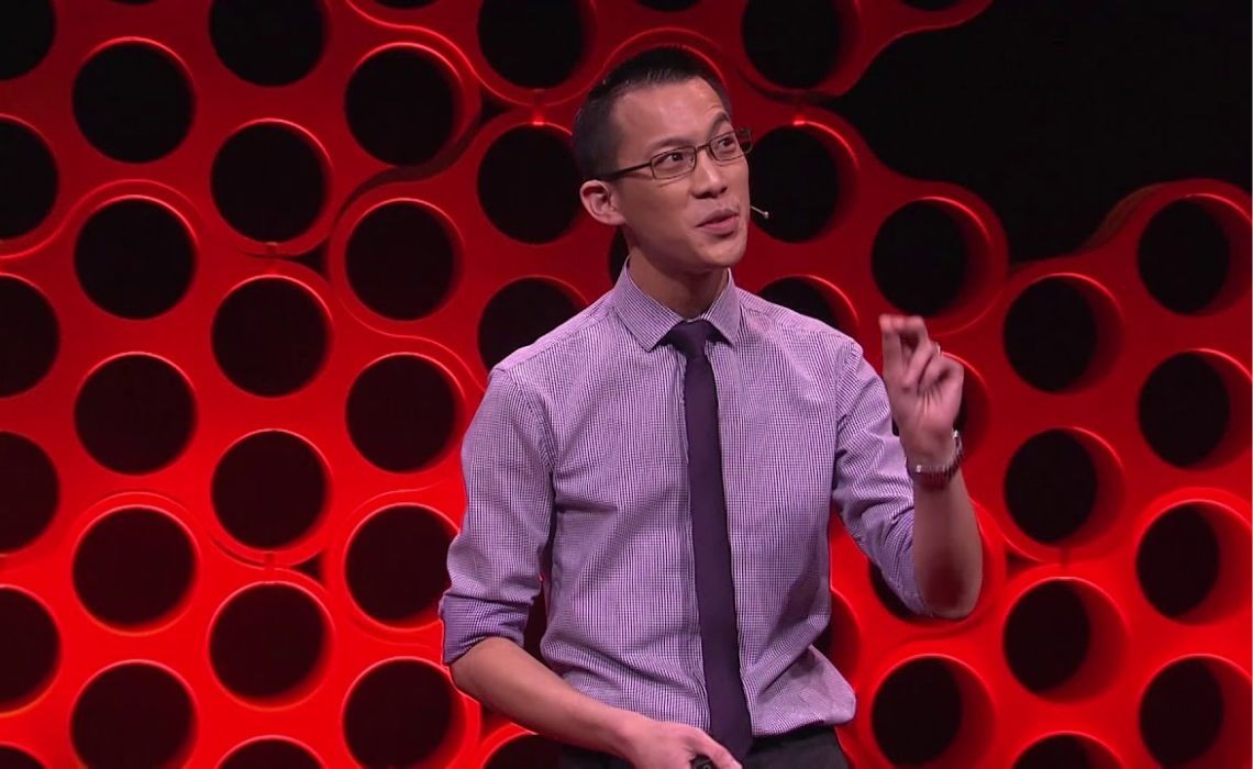 A man in front of a red-dotted background.