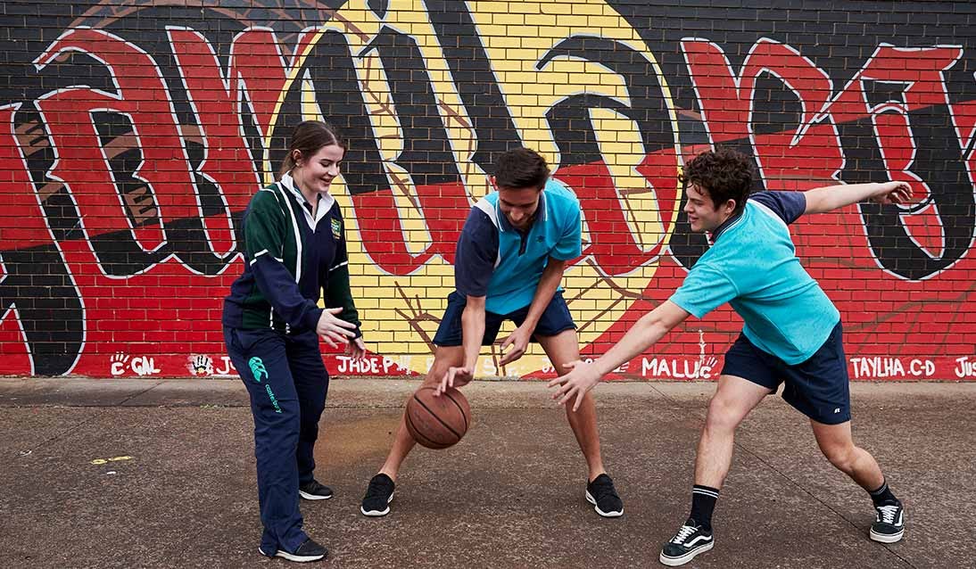 Two boys and a girl play basketball.