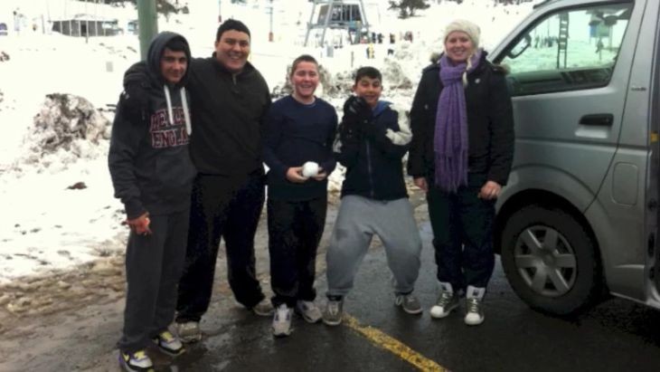 Students and a teacher standing in a car park near snow.