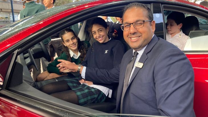 A man with students sitting in a car.