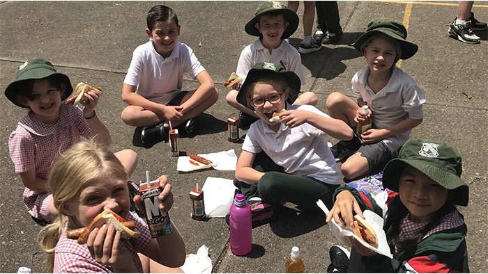 A group of children sitting in the playground having lunch