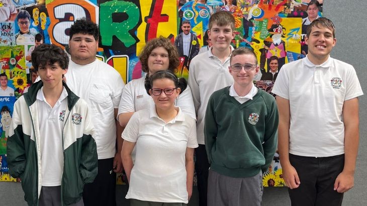 A group of students standing in front of an artwork.