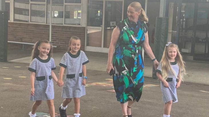 A principal walking with three small students.