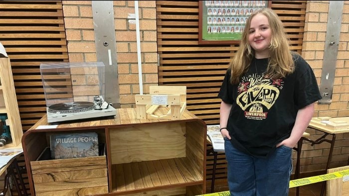 A young woman stands in front of a cabinet