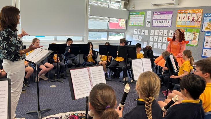 Two women with students playing recorders in a classroom.