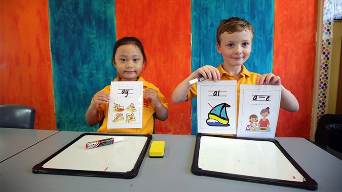 Two school children holding up drawings