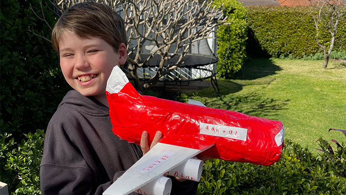 A young boy holding a model airplane made from recycled items
