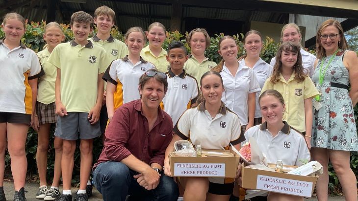 A man with a group of students including two holding boxes.