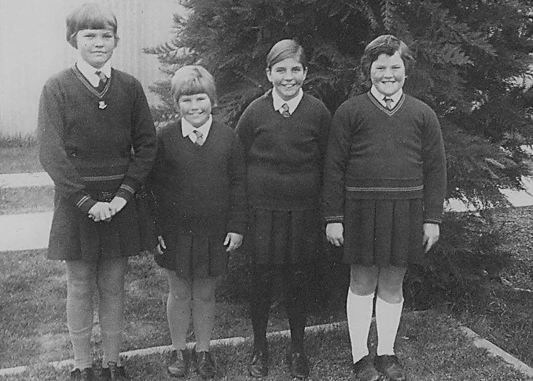 Black and white photo of four students standing outside.