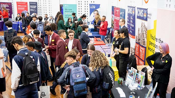Students walking between stalls at a careers expo.