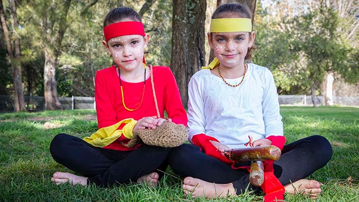 Two girls holding Aboriginal artefacts.