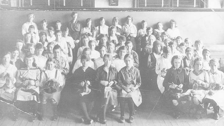 Students sitting in rows knitting.