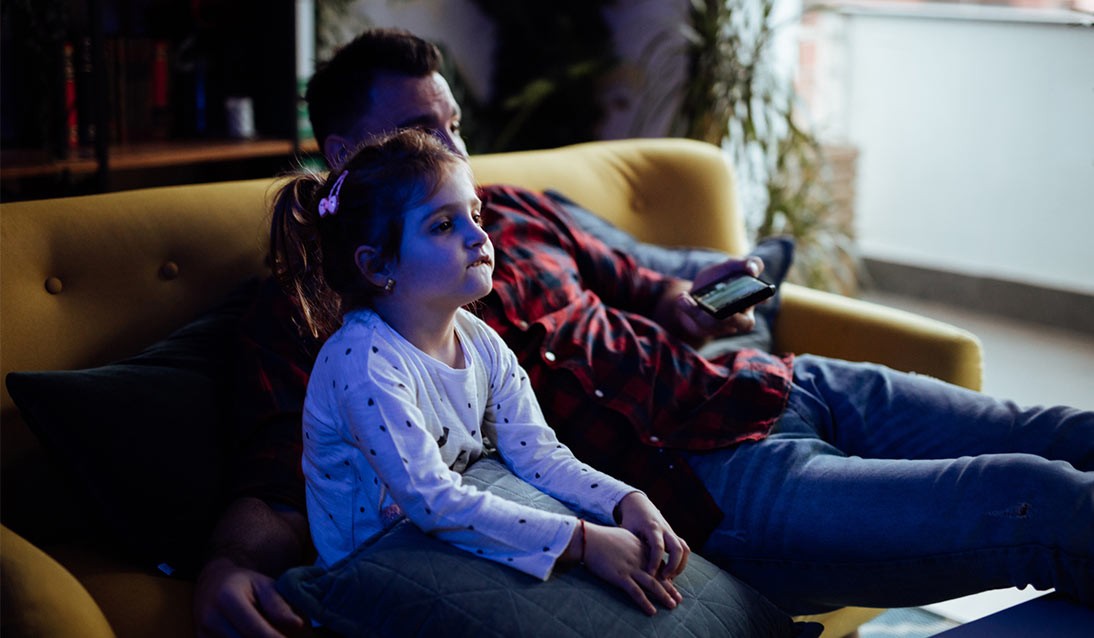 A child and father watching television.