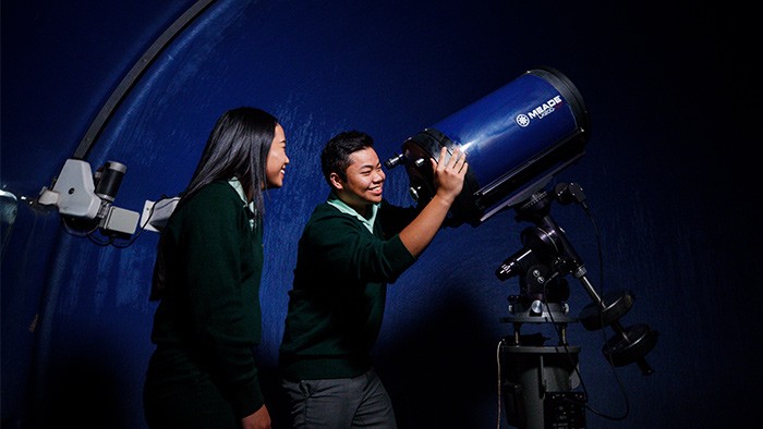 A male and female student using a telescope