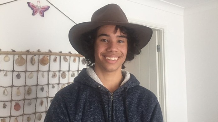 A boy wearing an aukubra hat smiling broadly