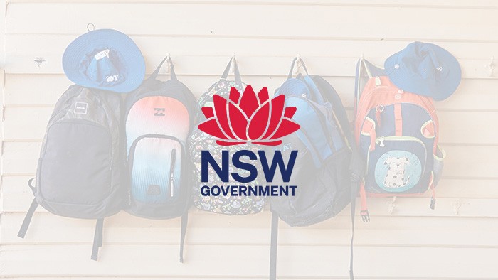 The NSW Government logo overlaying schoolbags hanging on hooks on a wall.