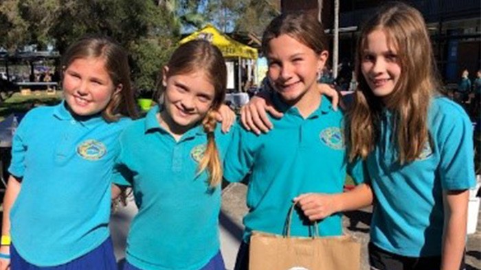 Four girls standing shoulder to shoulder facing the camera.