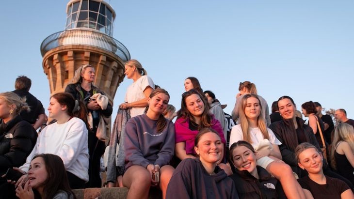 Students sitting in front of a lighthouse.