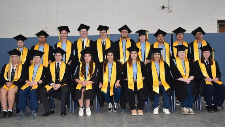 Students in two rows dressed in graduation gowns.