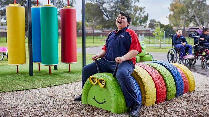 Student sitting on a caterpillar made of tyres.