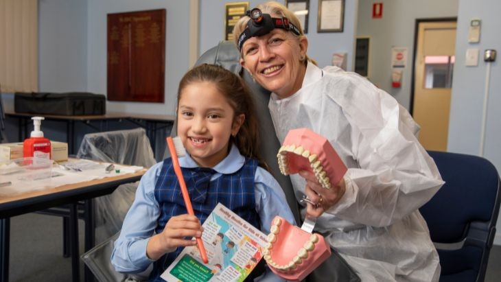 A student and dentist holding rubber teeth.